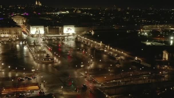 AERIAL: Vuelo sobre la Place de la Concorde en París, Francia por la noche con luces de tierra reflectantes húmedas y de ciudad luminosa — Vídeo de stock