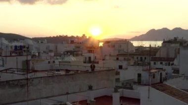 Little Town House 'un çatısında dikilen adam Tropik Ada Limanı ile Sunrise' da botları ve okyanusu olan arka planda dağları olan seyahat, günbatımı olan bir adam. 