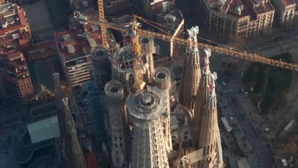 AERIAL: Close up Overhead Circling La Sagrada Familia with Cranes in Beautiful City Sunny Haze over Barcelona, Spain — стокове відео