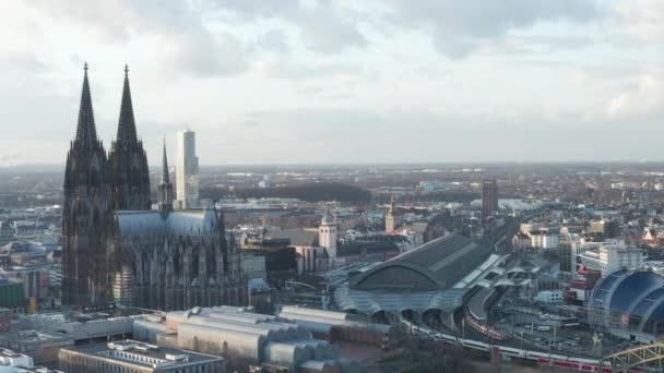 AERIAL: Rodeando la hermosa catedral de Colonia con la estación central de tren en la hermosa luz del sol brumosa — Vídeos de Stock