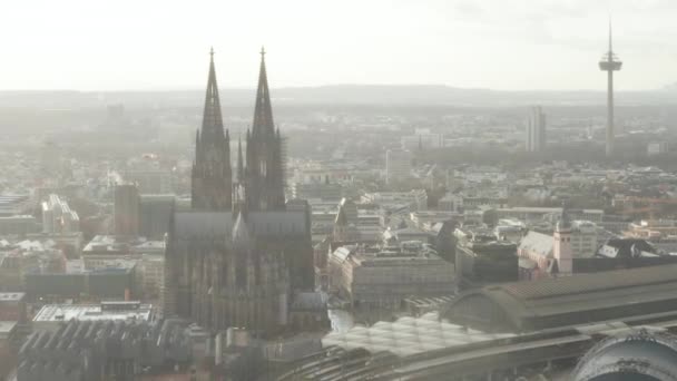 AERIAL: Κολωνία Hohenzollern Bridge και Θέα στον καθεδρικό ναό με κεντρικό σιδηροδρομικό σταθμό στο όμορφο θολό φως του ήλιου — Αρχείο Βίντεο