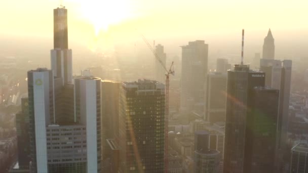 AERIAL: Utsikt över Frankfurt am Main, Tyskland Skyline med solsken mellan skyskrapor i vacker solnedgång solljus i Winter Haze — Stockvideo
