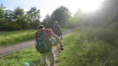 İki You Man, genç adam yeşil çimlerin üzerinde yürüyor Yazın elinde futbol ile Sunflair 