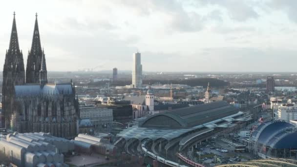 AERIAL: Rodeando la hermosa catedral de Colonia con la estación central de tren en la hermosa luz del sol brumosa — Vídeos de Stock