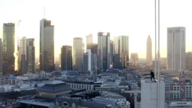 Kendine güvenen genç adam Frankfurt am Main, Almanya 'nın Skyline' ındaki çatıda yürüyor kışın güzel güneş ışığıyla