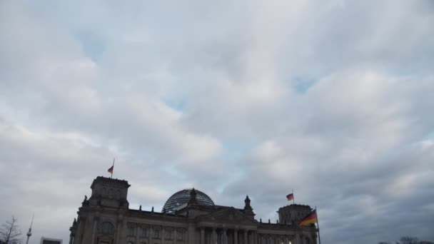 Широкий снимок Бундестага, Рейхстаг в Берлине, Германия с немецким флагом, размахивающим ветром в пасмурный день — стоковое видео