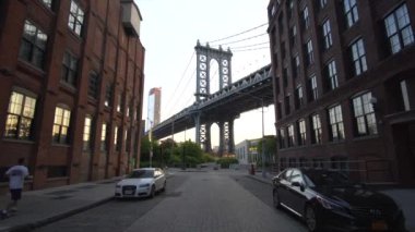 Dumbo 'dan Brooklyin Köprüsü Manzarası' na, yazın erken saatlerinde park etmiş araçlar ve aptal apartman daireleri ile Runner yanımızdan geçerken. 