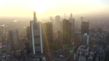 Frankfurt am Main 'in görüntüsü, Almanya gökdelenler arasında güneşli bir gökyüzü ile kışın güzel gün batımı sisinde
