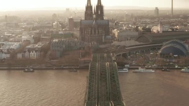 AERIAL: Widok na Kolonię Hohenzollern Bridge i widok katedry i wieży telewizyjnej w pięknym mglistym świetle słonecznym — Wideo stockowe