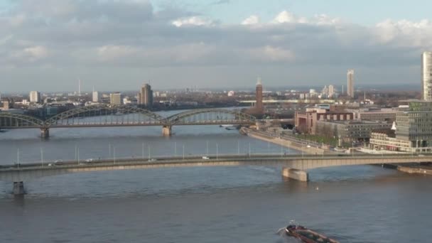 AERIAL: Vista sobre o rio Reno em Colônia Barco de carga passando sob uma ponte na bela luz do sol — Vídeo de Stock