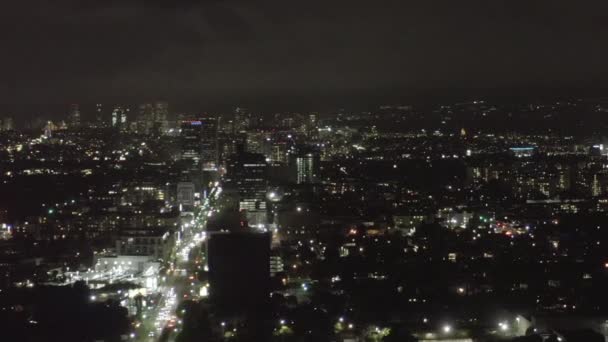 AERIAL: Sobre Dark Hollywood Los Angeles por la noche vista en Wilshire Blvd con nubes sobre el centro y City Lights — Vídeo de stock