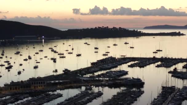 AERIAL: Cidade Pequena com Porto na Ilha Tropical, de manhã cedo com Barcos e Oceano na Cidade Pequena ao Nascer do Sol com Montanhas no Fundo Férias, Viagens, Pôr do Sol — Vídeo de Stock