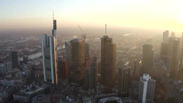 AERIAL: Utsikt över Frankfurt am Main, Tyskland Skyline med solsken mellan skyskrapor i vacker solnedgång solljus i Winter Haze — Stockvideo