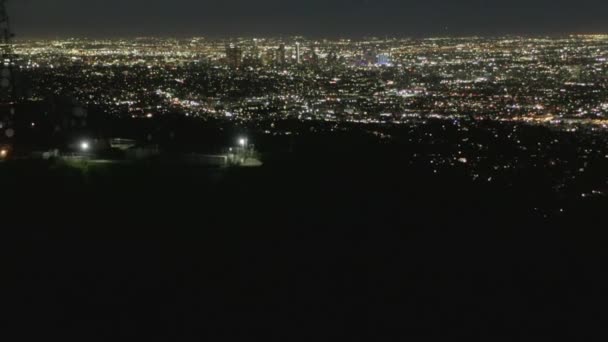 AERIAL: Spektakulärer Flug über Mount Lee und Hollywood-Zeichen bei Nacht mit Lichtern im Stadtbild von Los Angeles — Stockvideo