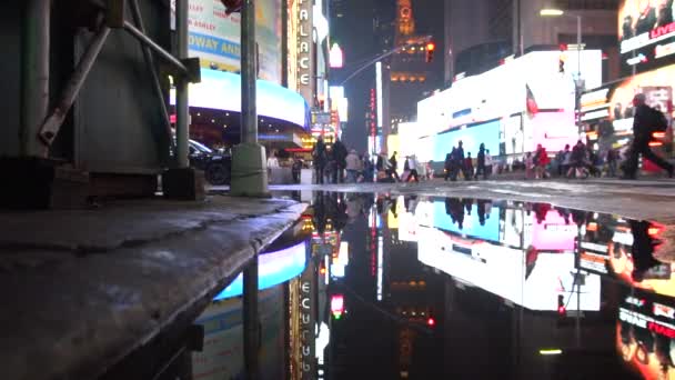 MOCIÓN LENTA: Luces de Times Square reflejándose en charco después de la lluvia en la ciudad de Nueva York por la noche Manhattan — Vídeos de Stock