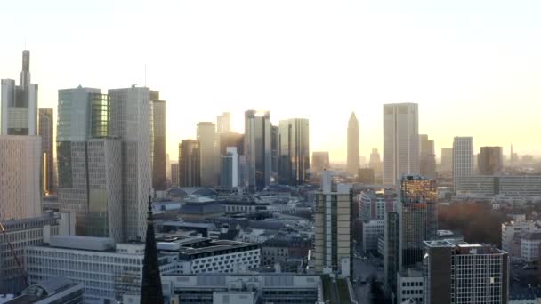AERIAL: Άποψη της Φρανκφούρτης am Main, Γερμανία Ουρανοξύστες με ηλιοφάνεια μεταξύ ουρανοξύστες στο Όμορφο Ηλιοβασίλεμα στο Χειμώνα Haze — Αρχείο Βίντεο