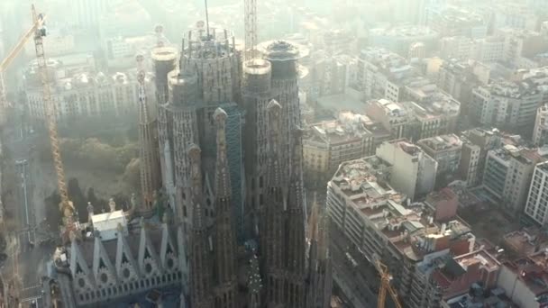 AERIAL: Närbild Cirkling La Sagrada Familia med tranor i vackra staden Sunny Haze över Barcelona, Spanien — Stockvideo