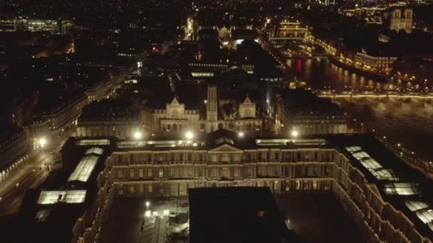 AERIAL: Flight over glowing Louvre Museum, Pyramid at Night in Paris, France — стоковое видео