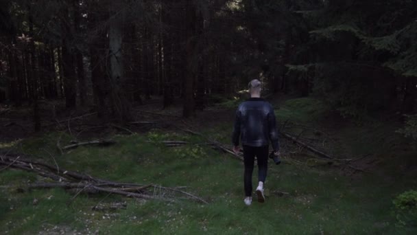 スローモーション:若い男、写真家カメラで森の中を歩き、夏の写真を撮る — ストック動画