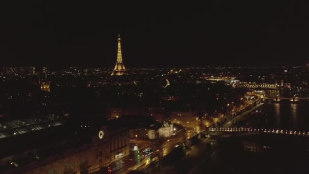 AERIAL: Vuelo en avión no tripulado inverso desde la Torre Eiffel, Tour Eiffel en París, Francia por la noche con luces de ciudad — Vídeo de stock