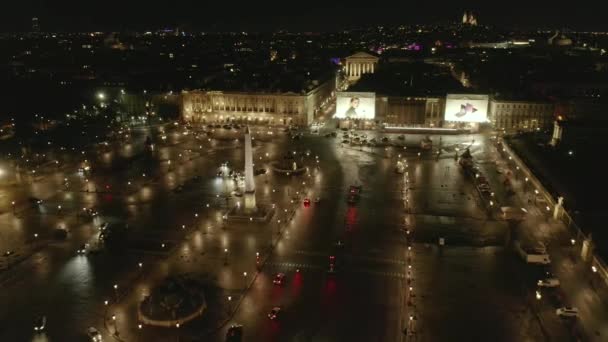 AERIAL: Vuelo sobre la Place de la Concorde en París, Francia por la noche con luces de tierra reflectantes húmedas y de ciudad luminosa — Vídeo de stock