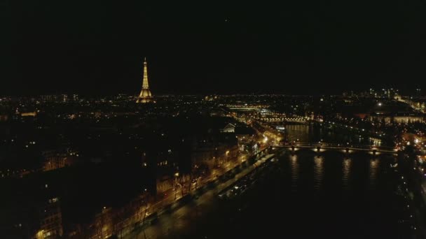 AERIAL: Vuelo en avión no tripulado inverso desde la Torre Eiffel, Tour Eiffel en París, Francia por la noche con luces de ciudad — Vídeos de Stock