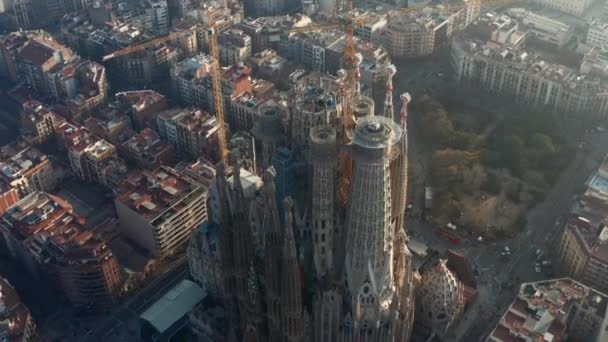 AERIAL: Närbild Cirkling La Sagrada Familia med tranor i vackra staden Sunny Haze över Barcelona, Spanien — Stockvideo