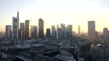 Frankfurt am Main 'in görüntüsü, Almanya gökdelenler arasında güneşli bir gökyüzü ile kışın güzel gün batımı sisinde
