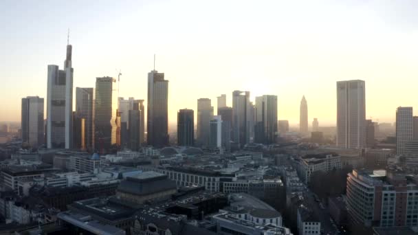 AERIAL: Blick auf Frankfurt am Main, Deutschland Skyline mit Sonnenflair zwischen Wolkenkratzern im schönen Sonnenuntergang im Winterdunst — Stockvideo