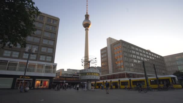 Alexander Platz, Berlin i soligt dagsljus med turister, Folk går runt och gul spårvagn Tåg passerar — Stockvideo