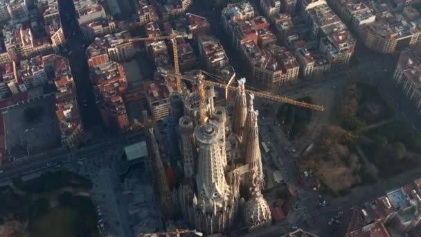AERIAL: Närbild Overhead Cirkling La Sagrada Familia med tranor i vackra staden Sunny Haze över Barcelona, Spanien — Stockvideo