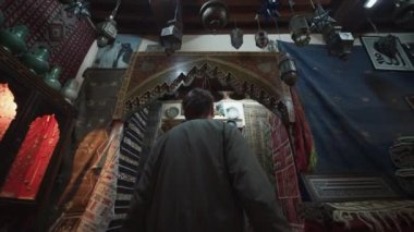 MoroCCO 'nun eski kasabasındaki eski renkli arabalarla eski bir dükkâna doğru yürüyen genç, öfkeli bir adam. 