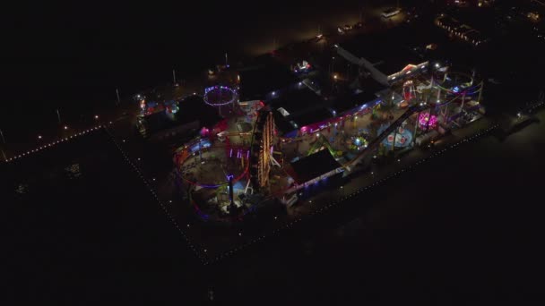 AERIAL: Beathtaking view on Santa Monica Pier at night with Ferris Wheel and colorful lights, — Stock Video