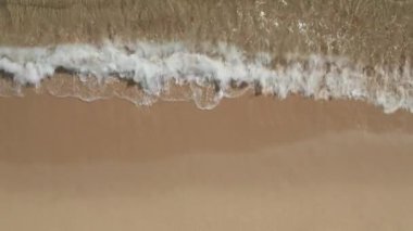 Güzel, genel tropikal plaj yukarıdan çekiliyor, kuş bakışı okyanus dalgaları yukarıdan boş bir sahile çarpıyor. 