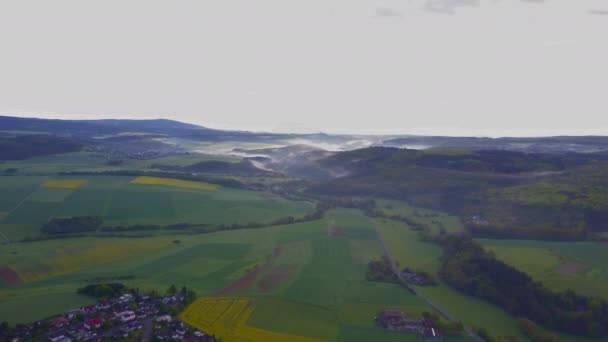 AERIAL: Flight over German fields, town, Nature with foggy landscape in the back, Sunshine, fog — стоковое видео