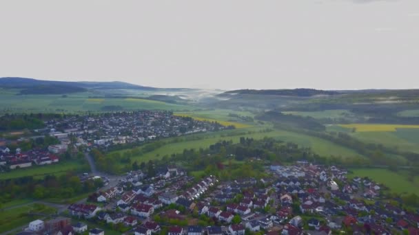 AERIAL: Voo sobre a cidade alemã com paisagem nebulosa na parte de trás, Sol, nevoeiro — Vídeo de Stock