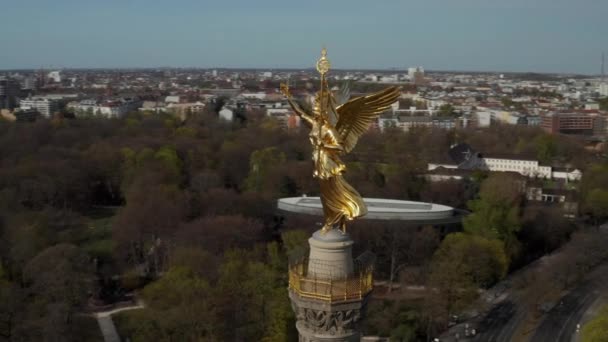 AERIAL: Cierre del círculo alrededor de Berlín Victory Column estatua de oro Victoria en la hermosa luz del sol y Berlín, Alemania City Scape Skyline en el fondo de tierra. — Vídeos de Stock