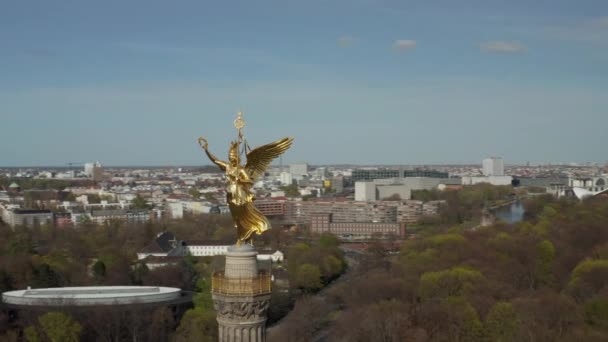 AERIAL: Close Up Circling around Berlin Victory Column Golden Statue Victoria in Beautiful Sunlight and Brandenburg Gate in Background — Stock Video