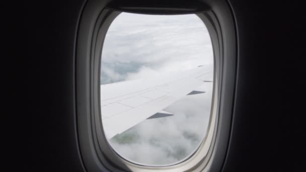 Mire fuera de la ventana del avión en las nubes en movimiento con vista en el ala — Vídeos de Stock