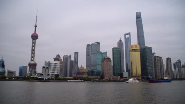 Pohled na Šanghaj Skyline přes řeku Bund s velkou lodí jedoucí přes řeku v zamračený den — Stock video