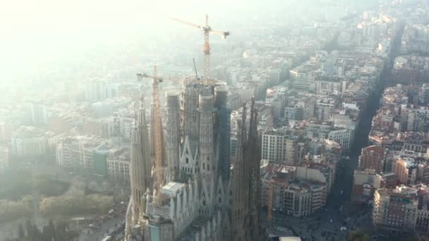 AERIAL: Circulando La Sagrada Familia com guindastes em bela cidade Sunny Haze em Barcelona, Espanha — Vídeo de Stock