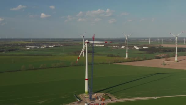 AERIAL: Bred utsikt över vindkraftverk under uppbyggnad bygger på rika gröna jordbruksområdet för förnybar energi och hållbar utveckling — Stockvideo