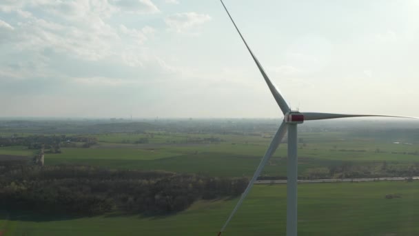 AERIAL: primer plano de molino de viento girando por la fuerza del viento y generando energía renovable de una manera ecológica verde para el planeta sobre hermoso campo de agricultura verde — Vídeos de Stock