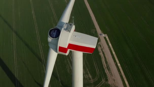 AERIAL: Close-up van windturbine in aanbouw wordt gebouwd op een rijk groen landbouwveld — Stockvideo