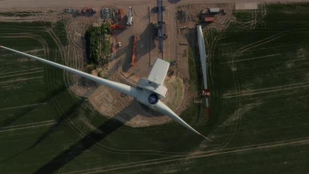 AERIAL: Közel felső drón nézet repülés felett Wind Turbine építés alatt álló épül gazdag zöld mezőgazdaságban — Stock videók