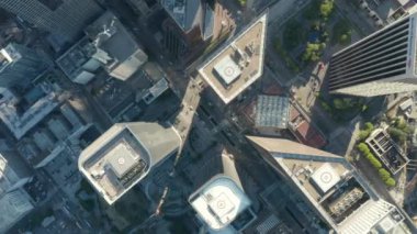 Helikopter, Los Angeles şehir merkezindeki gökdelenlerin çatıları ve araba trafiğinin önünden geçerken, Los Angeles 'ın aşağısına doğru yavaşça iniyor ve daire çiziyor. 