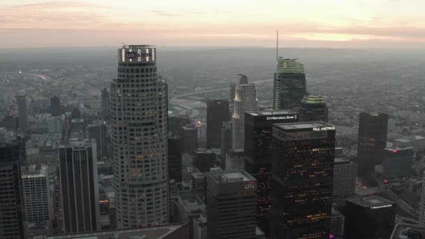 AERIAL: lélegzetelállító fordított repülés a felhőkarcolók Los Angeles belvárosában, Kaliforniában a gyönyörű naplementében — Stock videók