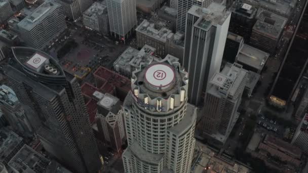 AERIAL: Dech beroucí široký záběr kolem americké banky obrovský mrakodrap Top, Heli Pad v centru Los Angeles, Kalifornie při západu slunce, — Stock video