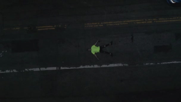 AERIAL: Młody człowiek leżący na ulicy powoli Birds eye Zobacz lot nad centrum Los Angeles California Grand Avenue w pięknym Sunrise Light z widokiem na dachy drapaczy chmur i ruchu samochodowego przechodzącego — Wideo stockowe