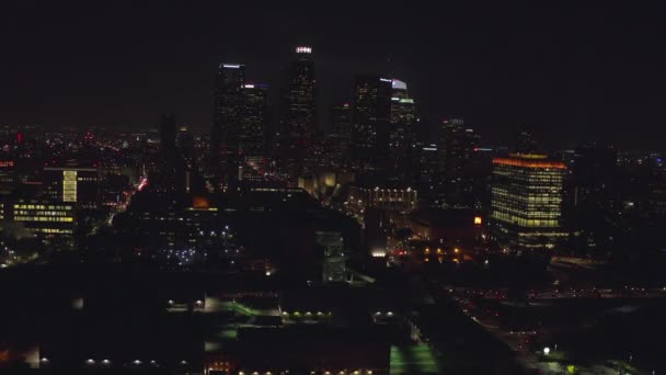 AERIAL: Volando hacia los rascacielos del centro, Skyline Los Angeles, California por la noche con luces de la ciudad , — Vídeo de stock